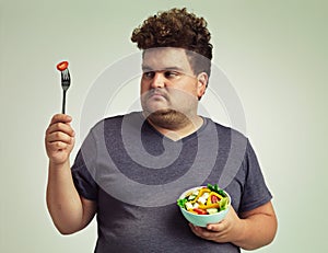 Its you and me, tomato. Studio shot of an overweight man holding a bowl of salad.