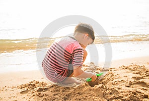 ittle boy playing sand on the beach summer time