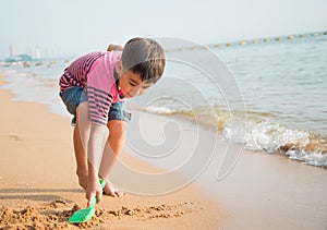 ittle boy playing sand on the beach summer time