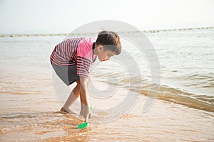 ittle boy playing sand on the beach summer time