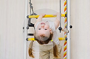 Ittle girl hangs on the stairs upside down