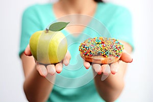Itâ€™s hard to choose healthy food concept, with woman hand holding an green apple and a calorie bomb donut