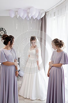 Ivano-Frankivsk, Ukraine, September 8 2019: Friends lace corset on the bride`s dress. Bridesmaids dress the bride with a slender