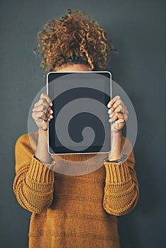 Ive been meaning to show this to you. Studio shot of a young woman holding a digital tablet with a blank screen against