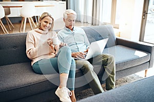 Ive got coffee and hes got connectivity, both happy. mature couple using a laptop on the sofa at home.