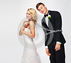 Ive got my man now. Smiling young bride pulling her groom along by a chain wrapped around his waist.