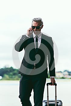 Ive just landed. Cropped shot of a handsome mature businessman walking with his luggage outside of the airport.