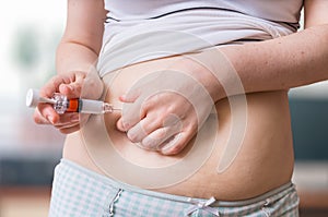 IVF and infertility treatment concept. Patient is injecting hormones to abdomen with syringe