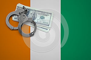 Ivory Coast flag with handcuffs and a bundle of dollars. The concept of breaking the law and thieves crimes