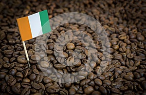 Ivory Coast flag sticking in roasted coffee beans. Concept of export and import