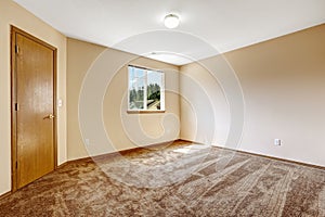 Ivory empty room with brown carpet floor and wooden door