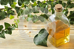 Ivy leaf and syrup in a bottle on a natural wooden table. Production of cough medicine with ivy extract. pharmaceutical industry