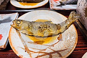 Iwana fish or Salvelinus grilled on a plate topped with Japanese sauce water on table photo