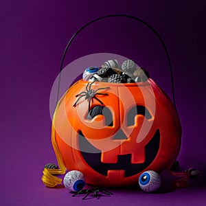 Jack-o-lantern bag full of candy on  dark purple background, square format