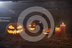 Jack-O-Lantern Halloween pumpkins on rough wooden planks with candles