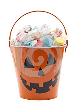 A Jack O Lantern Pumpkin Bucket Filled with Wrapped Saltwater Taffy Isolated on a White Background