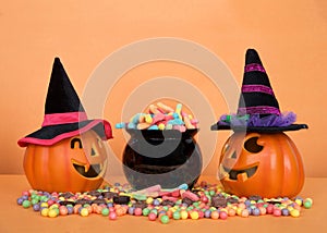 Jack o lanterns wearing witch hats with cauldron of candy