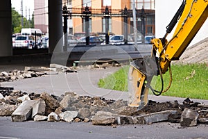 Jackhammer excavator breaks curbs along the road