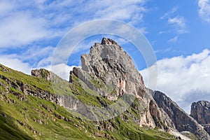 The jagged cliffs of Seceda stand out against the vibrant green hills, with intricate rock textures highlighted by sunlight under photo