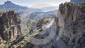 Jagged cliffs tower over the twisting road as if guarding the hidden treasures of the rugged landscape. . AI generation