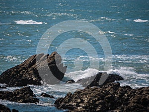 Jagged rocks jutting from blue ocean photo