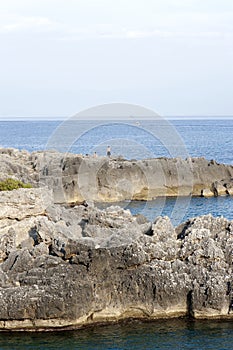 A jaggy inlet with the sea dashing against the horizon at sunset. Cove, go fishing, horizon.