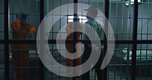 Jailer with police baton stands in front of cells photo