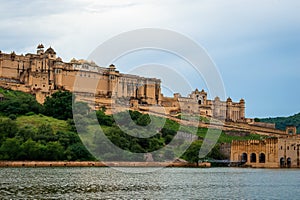 Jaipur, Rajasthan, India, September 7, 2020 : Intricately carved gateway Amer Fort Palace with maota lake and clouds in sky