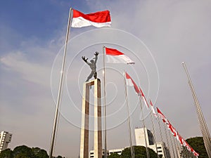 Jakarta, August 13-2023 : Rows of Indonesian flags in Banteng Square with the West Irian Liberation Statue in the background