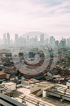 Jakarta Cityscape with high rise, skyscrapers and red tile hip roof local buildings with fog in the morning