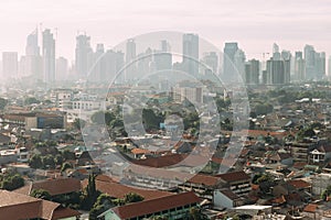 Jakarta Cityscape with high rise, skyscrapers and red tile hip roof local buildings with fog in the morning