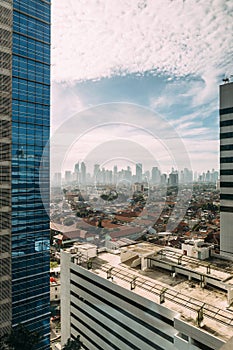 Jakarta Cityscape with high rise, skyscrapers and red tile hip roof local buildings with fog in the morning