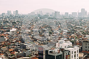 Jakarta Cityscape with high rise, skyscrapers and red tile hip roof local buildings with fog in the morning