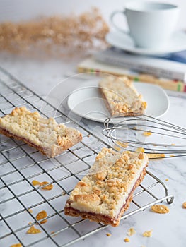 Jam crumble bar on cake rack and white dish, decorated with egg whisk, selective focus. fresh homemade bakery concept.