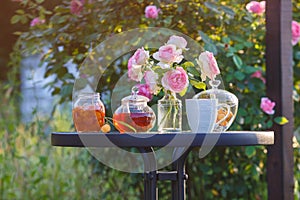 Jam in glass jar. Romantic dinner in the garden under a rose bush.