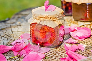 Jam from rose with rose petals on stump