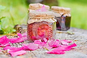 Jam from rose with rose petals on stump