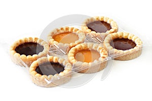 Jam tarts in plastic box on white background.