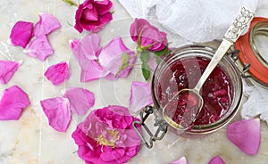 Jam of tea rose petal in glass jar on light marble background. Flower confiture. Healthy food. Copy space