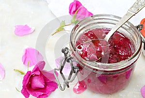 Jam of tea rose petal in glass jar on light marble background. Flower confiture. Healthy food. Copy space