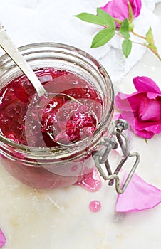 Jam of tea rose petal in glass jar on light marble background. Flower confiture. Healthy food. Copy space