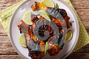 Jamaican food: jerk chicken drumstick with lime closeup on a plate. horizontal top view from above photo