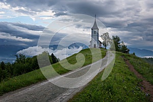 Jamnik church on a hillside in the spring, foggy weather at sunset in Slovenia, Europe. Mountain landscape shortly after spring ra