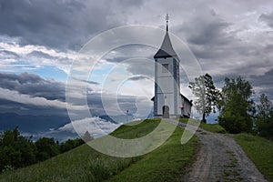 Jamnik church on a hillside in the spring, foggy weather at sunset in Slovenia, Europe. Mountain landscape shortly after spring ra