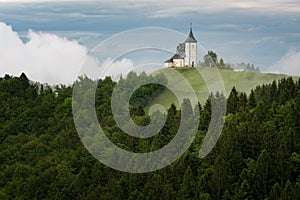 Jamnik church on a hillside in the spring, foggy weather at sunset in Slovenia, Europe. Mountain landscape shortly after spring ra