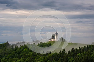 Jamnik church on a hillside in the spring, foggy weather at sunset in Slovenia, Europe. Mountain landscape shortly after spring ra