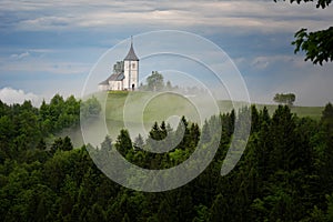 Jamnik church on a hillside in the spring, foggy weather at sunset in Slovenia, Europe. Mountain landscape shortly after spring ra