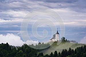 Jamnik church on a hillside in the spring, foggy weather at sunset in Slovenia, Europe. Mountain landscape shortly after spring ra