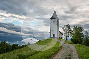 Jamnik church on a hillside in the spring, foggy weather at sunset in Slovenia, Europe. Mountain landscape shortly after spring ra