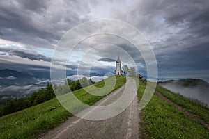 Jamnik church on a hillside in the spring, foggy weather at sunset in Slovenia, Europe. Mountain landscape shortly after spring ra